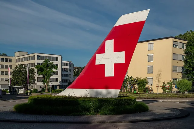 Rotatoria a Kloten con una coda di aeroplano stilizzata nei colori svizzeri – rappresentazione sfocata